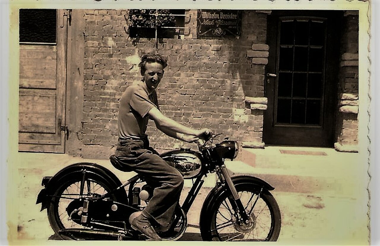 Schwarz-weiß-Foto: Junger Mann auf Motorrad.
