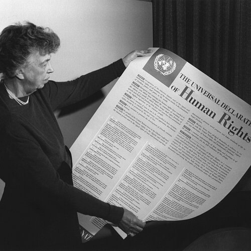 Eleanor Roosevelt mit einem Poster der Deklaration in englischer Sprache. FDR Presidential Library & Museum, CC BY 2.0 <https://creativecommons.org/licenses/by/2.0>, via Wikimedia Commons https://commons.wikimedia.org/wiki/File:Eleanor_Roosevelt_UDHR.jpg