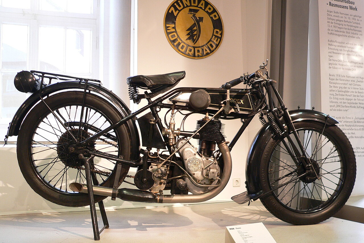Farbfoto: Schwarzes Motorrad auf Potest mit einem Infoaufsteller davor. Im Hintergrund ist eine Texttafel des Museums im Anschnitt sichtbar.