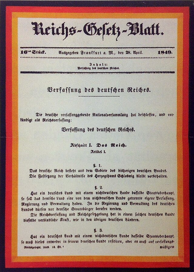 Farbfoto: Dokument mit schwarz-rot-goldenem Rand und altdeutschem Text.