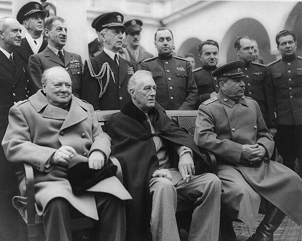 Gruppenfoto nach dem Abschluss der Verhandlungen in Jalta. Von links: Winston Churchill, Franklin D. Roosevelt und Josef Stalin, https://commons.wikimedia.org/wiki/File:Jalta_1945.jpg?uselang=de, als gemeinfrei gekennzeichnet,  ausgeschnitten von HLZ, CC0 1.0