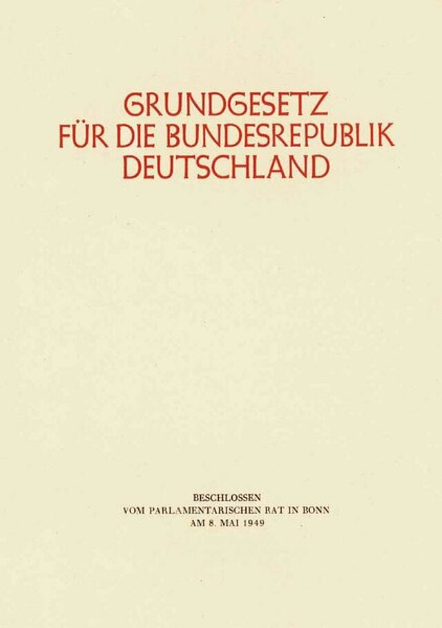 Farbfoto: Buch mit der Aufschrift: Grundgesetz für die Bundesrepublik Deutschland, darunter: Beschlossen vom Parlamentarischen Rat in Bonn an 08. Mai 1949.