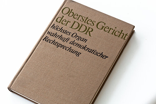 Farbfoto: Braunes Buch mit der Aufschrift: Oberstes Gericht der DDR, höchstes Organ wahrhaft demokratischer Rechtssprechung